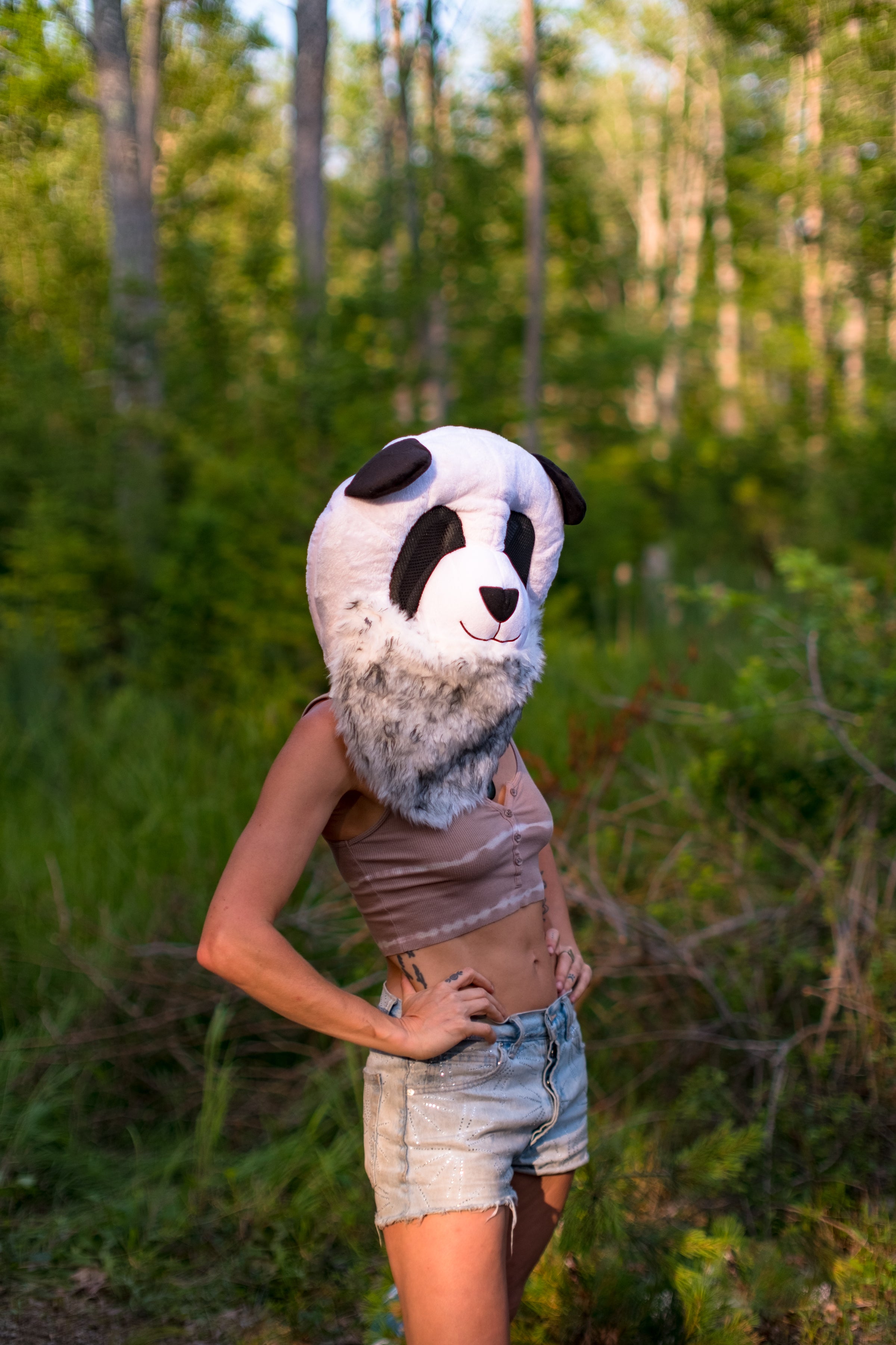Person wearing a panda mask in a forest setting