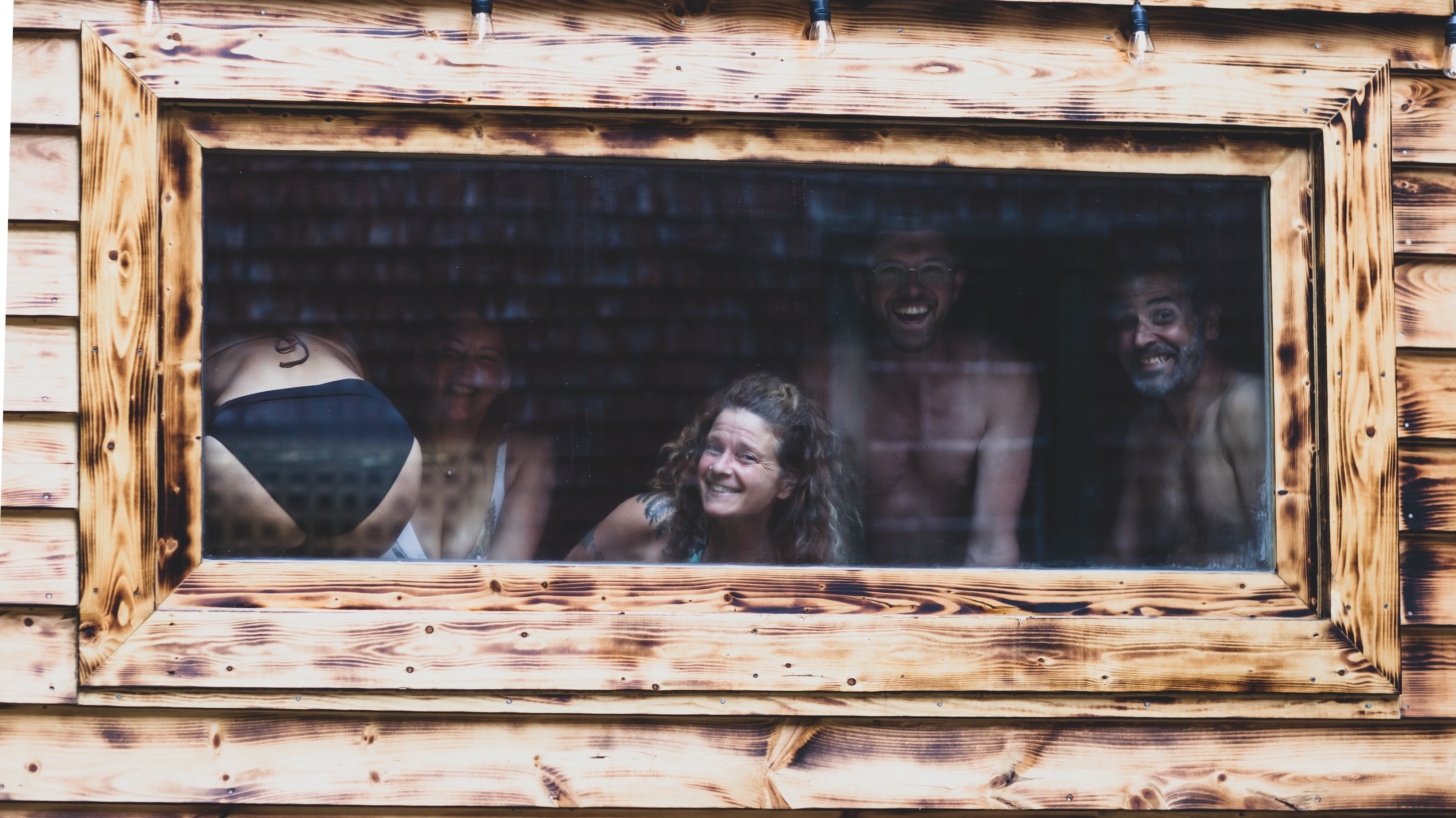 People peeking through a wooden window frame OF SAUNA